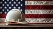 © olegganko - Rustic hard hat resting on wooden surface with American flag backdrop in a construction setting