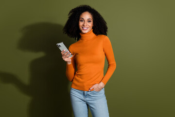 Poster - Photo of cheerful pretty lady dressed orange turtleneck chatting modern gadget empty space isolated green color background