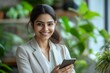 © Joaquin Corbalan - Indian business woman in formal attire using cellphone while smiling in a modern office space