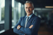 © Enrique - Happy middle aged business man ceo standing in office arms crossed