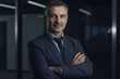 © Enrique - Happy middle aged business man ceo standing in office arms crossed
