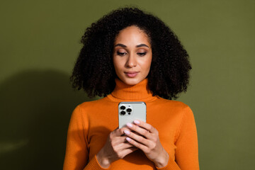 Wall Mural - Photo of cheerful pretty lady dressed orange turtleneck texting sms modern gadget empty space isolated green color background