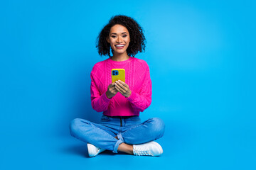 Sticker - Full body photo of attractive young woman sit floor hold device dressed stylish pink clothes isolated on blue color background