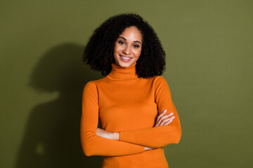 Wall Mural - Photo of cheerful pretty lady dressed orange turtleneck arms crossed empty space isolated green color background