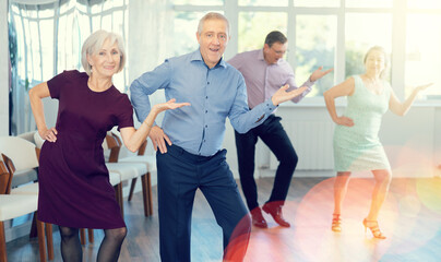 Couple of elderly man and elderly woman dancing twist in studio