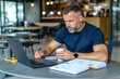 © Sanchai - Entrepreneur working on a business plan in a cafÃ©, with a laptop, coffee, and notebook on the table