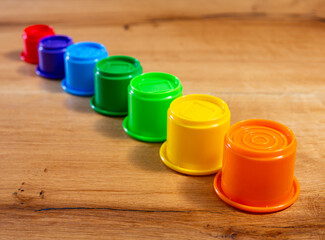 Childrens toy plastic cup pyramid made of multicolored elements. Parts of kids toy of different sizes are arranged in row in descending order of size and magnitude, piled up