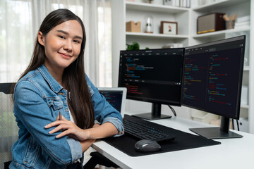 Wall Mural - Young Asian in IT developer looking at camera to present with online information on pc with coding program data application, wearing jeans shirt. surround by safety analysis two screens. Stratagem.