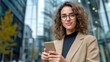 © Lens Legacy - A confident woman with curly hair in a blazer using her smartphone, stands in a bustling urban area, exuding professionalism and modern connectivity.