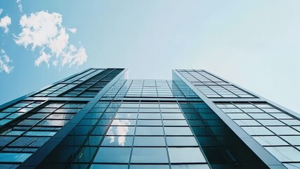 Aufkleber - A sleek glass building stands tall against a bright blue sky, reflecting clouds and sunlight, showcasing modern architecture and urban design.