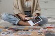 © New Africa - Creating vision board. Woman cutting out picture on floor indoors, closeup