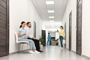 Sticker - Patients waiting for appointment and doctor in hospital hallway, selective focus