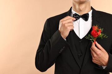 Canvas Print - Groom in suit with stylish boutonniere on beige background, closeup. Space for text