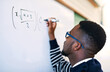 © SometimesNever/peopleimages.com - Teaching, classroom and black man writing on whiteboard for math lesson, learning and examination. Education, university and teacher write equation for knowledge, assignment and studying in college