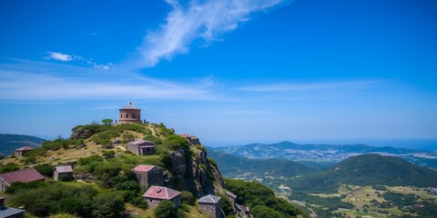 Sticker - A picturesque view of a mountaintop with several small buildings and a clear blue sky.