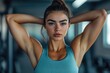 © khalid_spk - A focused young woman in athletic wear, standing in a gym with her arms behind her head