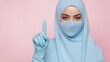 © Trusha - A woman wearing a blue hijab and a blue surgical mask. She is pointing to the sky with her finger