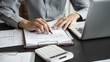 © Wanda - Asian business man holding paper document calculating tax insurance managing budget