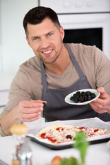 man cooking homemade pizza in a home kitchen