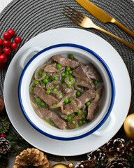 Strips of beef cooked with onion and peas. Top view table with Christmas decoration.