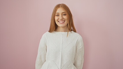 Canvas Print - A smiling young caucasian woman with redhead hair, casually dressed, stands isolated against a pink background.