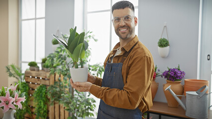 Smiling man holding plant in sunlit flower shop, conveying a sense of freshness and retail business.