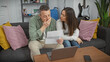 © Krakenimages.com - A concerned woman comforts a man holding a paper in a cozy living room with a laptop and guitar in the background.