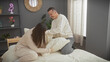 © Krakenimages.com - A happy couple enjoys a playful moment together on the bed in a cozy bedroom, evoking love and comfort.