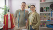 © Krakenimages.com - Confident man and woman designers pose in a bright tailor shop filled with cloth, thread, mannequin, and sewing tools.