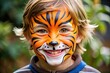© Sandra - Vibrant orange and black face paint transforms a smiling child's face into a fierce tiger, with whiskers and stripes adding a playful touch.