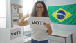 © Krakenimages.com - Woman voting in a brazilian polling station holding a vote sign and showing a thumbs-up gesture with a flag in the background indoors