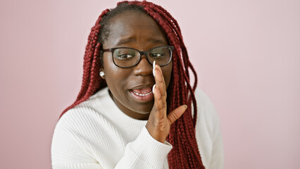 Canvas Print - African american woman with braids whispering over isolated pink background,