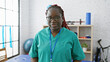 © Krakenimages.com - An african american woman with braids smiles in a rehab clinic's physiotherapy room, portraying a professional and caring demeanor.