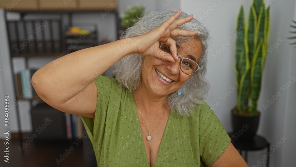Elderly woman with grey hair smiling and making a circle gesture with ...