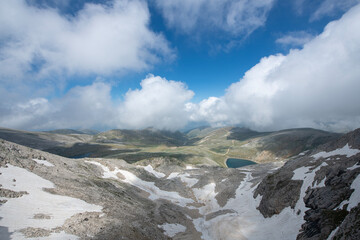 Snowy mountains and blue sky in the background. Snowy mountains with magnificent white clouds. Uludağ hiking routes. Clouds over Bursa Uludağ mountains. Blue sky, snowy and cloudy hills.