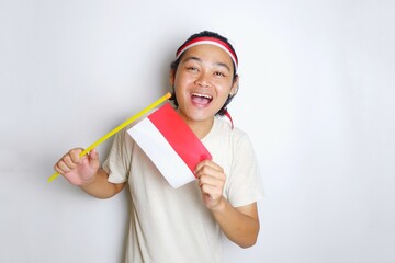 Portrait of an Indonesian man with long hair with a headband and red shirt celebrating Indonesian Independence Day with high nationalism on an isolated white background