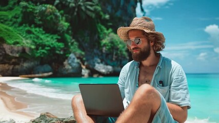 Poster - A man sits comfortably on the beach, focused on his laptop while enjoying the tropical environment and stunning views of the turquoise sea and palm trees around him.