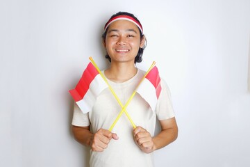 Portrait of an Indonesian man with long hair with a headband and red shirt celebrating Indonesian Independence Day with high nationalism on an isolated white background