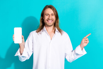 Poster - Photo of cheerful positive guy dressed white shirt typing modern device pointing emtpy space isolated turquoise color background