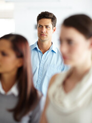 Wall Mural - Meeting, annoyed and man in office with doubt, questions and unhappy employee protest at creative agency. Workshop, human resources and business people at seminar with teamwork, irritated or confused