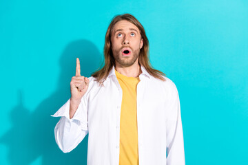 Canvas Print - Photo of attractive funny guy wear white shirt pointing finger up emtpy space isolated blue color background