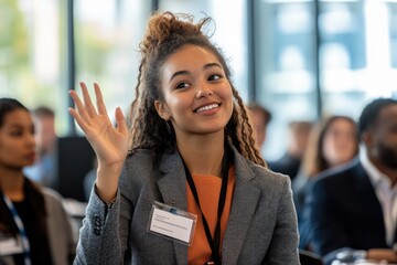 A young woman in a conference setting, enthusiastically raising her hand to ask