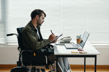 Wall Mural - Man with disability doing online work on tablet pc during his work in office