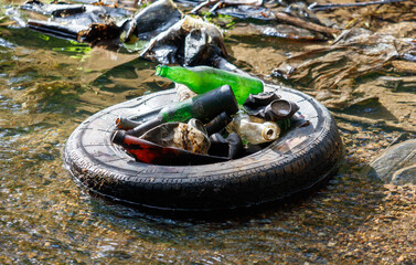 Wall Mural - A tire is floating in a body of water with trash and bottles