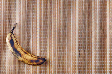 Wall Mural - An overripe banana lies on a bamboo napkin.