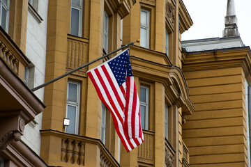 Striped American flag with symbols of all states in form of stars flies in flagpole on building, symbol of the American Dream and freedom