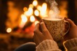 © Nico - Close-up of a Hand Holding a Steaming Mug with a Fireplace in the Background