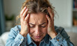 © Celt Studio - Frustrated woman holding her head in pain, suffering from intense headache or migraine. Depressed female in distress, feeling stressed and overwhelmed, experiencing health problems