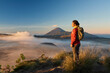 © Asia Pics - Asia, Indonesia, Java, Bromo Semeru national park, mature female tourist trekking at mount Bromo at sunrise, standing at viewpoint admiring view