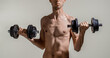 © Yevhen - Skinny man, dumbbells. Skinny man goes in for sports, builds muscles. Health care concept. Workout gym sport motivation concept. Man holding dumbbell in hand. Thin man in sports with dumbbells